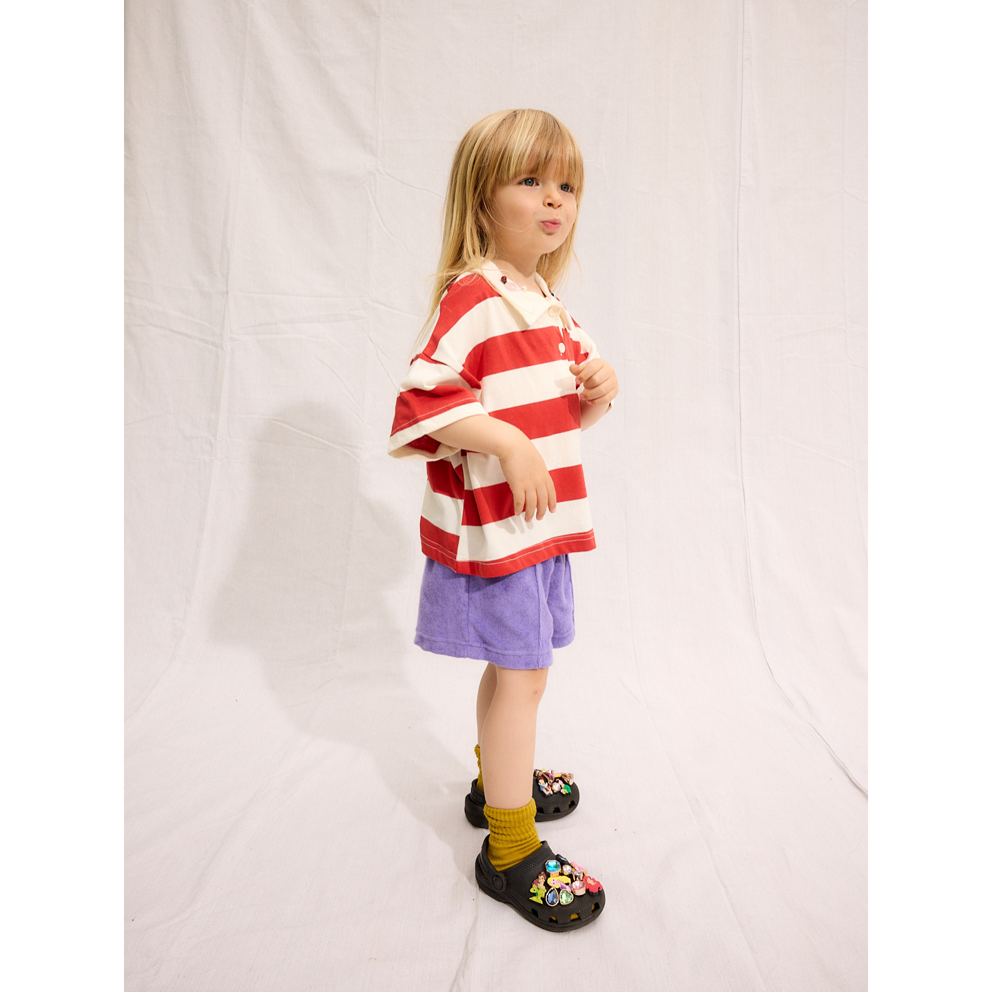 Purple | A child is wearing purple Everyday Terry Shorts with the Rugby Tee in Red