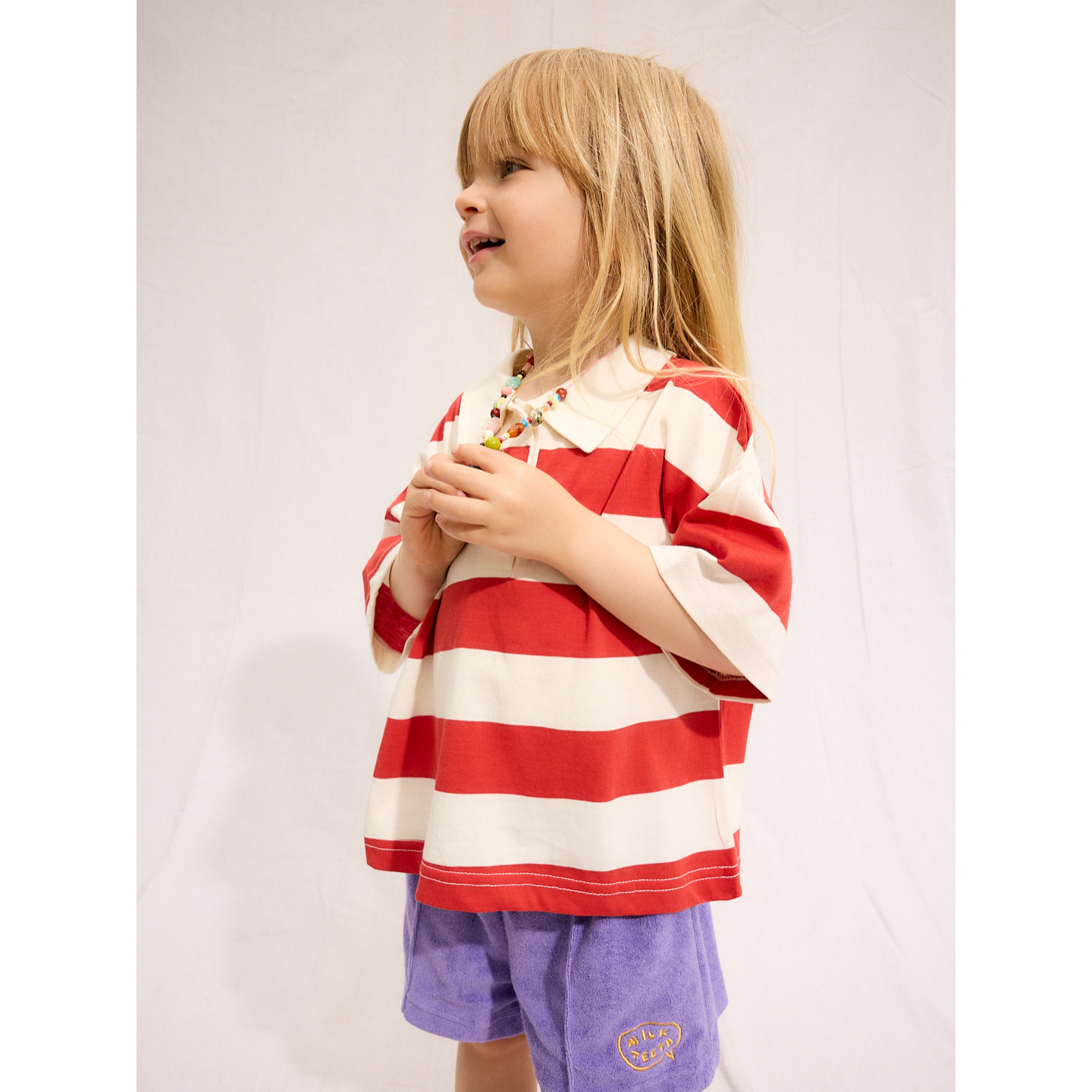 Purple | A child is wearing purple Everyday Terry Shorts with the Rugby Tee in Red