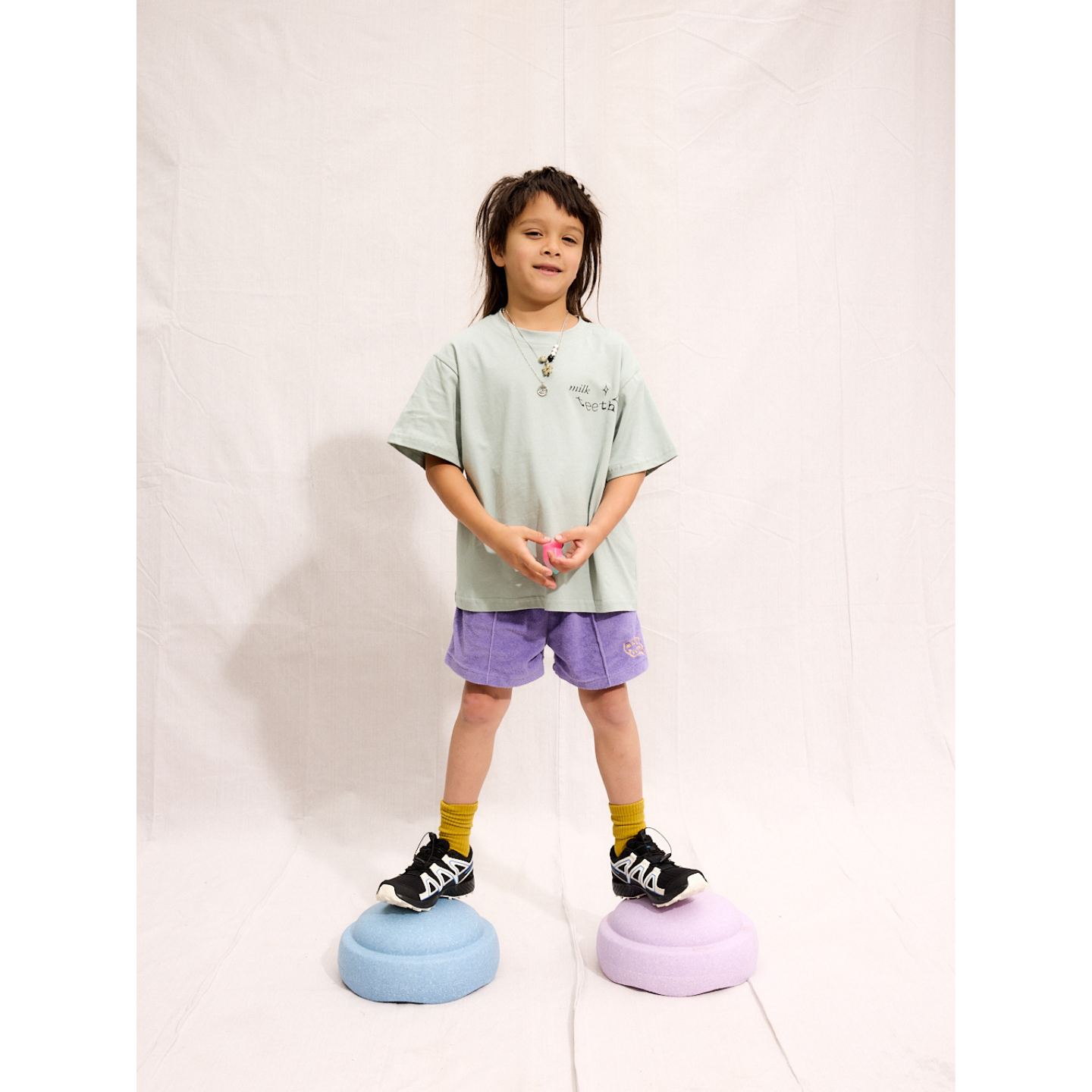 Purple | A child is wearing purple Everyday Terry Shorts with the mint Milk Teeth tee