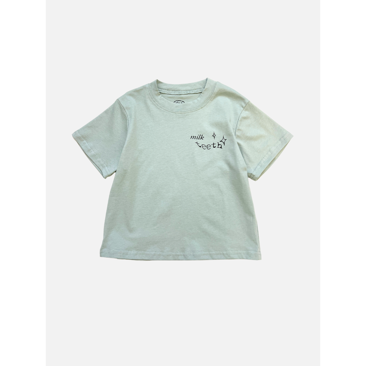 Mint | Mint short-sleeve MILK TEETH TEE featuring “milk teeth” and small star graphics, artist-designed and printed in black on the upper left chest.