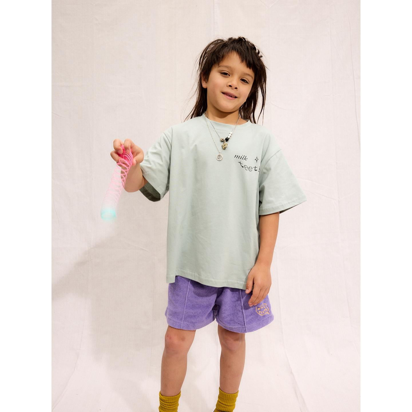 Purple | A child is wearing purple Everyday Terry Shorts with the mint Milk Teeth tee