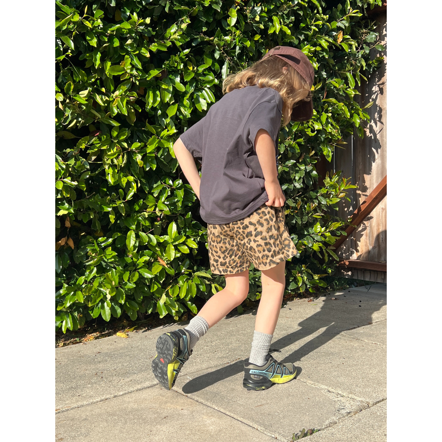 Charcoal | A child is wearing a charcoal tee with the Milk Teeth cap and leopard shorts