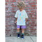 Ivory | A child Is wearing an ivory colorway of the fruit face tee with purple shorts.