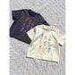 Ivory | Both colorwasy of the fruit face tee are laid flat on a quilt