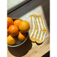 Marigold | A bowl of oranges sits on a wooden surface next to a pair of comfy, yellow and white STRIPE SOCKs.