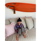 Child sitting on a couch with an orange surfboard above