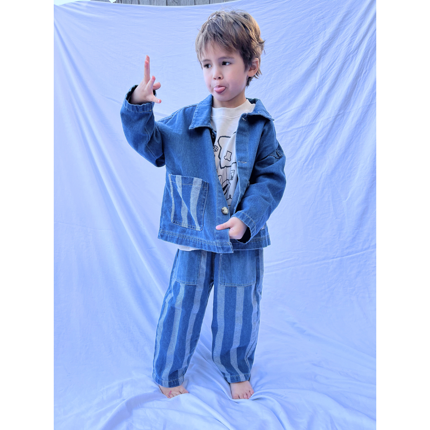 Medium Wash | A child wearing a blue denim jacket and the Stripe Double Trouble Jeans with an elasticated waist stands on a white backdrop.